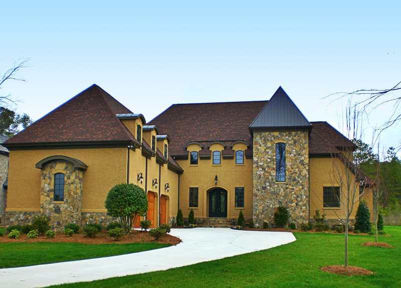 House plan exterior with a stucco finish, stone accents, multiple gables, dormers, and a three-car garage.