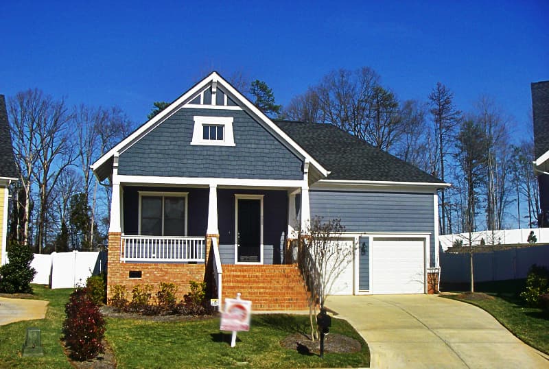 House plan exterior: Two-story Modern Farmhouse with covered front porch, brick accents, gabled dormer, and attached two-car garage.