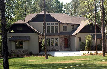 House plan exterior featuring a two-story design with stacked stone accents, multiple gables, and a prominent front entrance with arched windows.