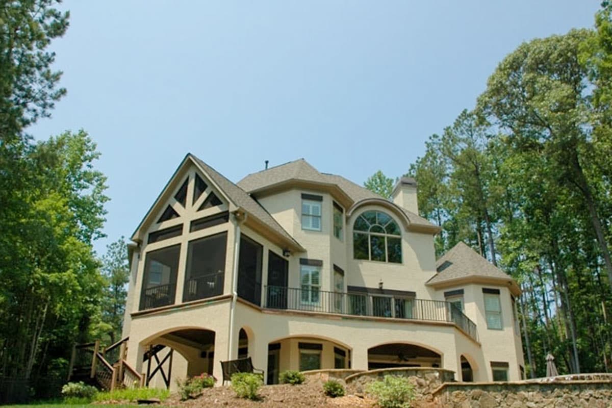 House plan exterior with arched windows, screened porch, and multiple gables.