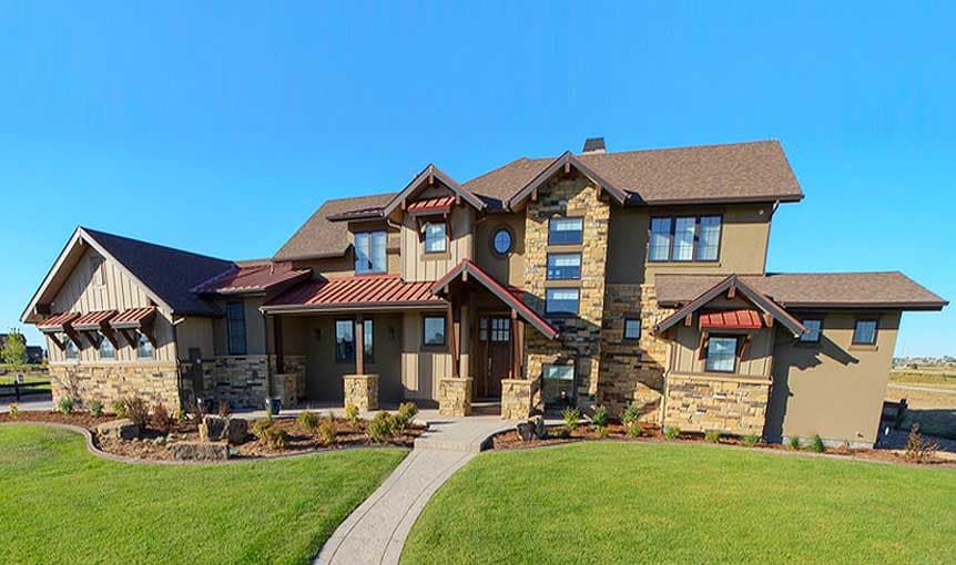 House plan exterior with stone and wood siding, multiple gables, metal roof accents, and a covered entry.
