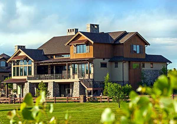 House plan exterior: This two-story modern home features multiple gables, stone accents, a covered porch, and large windows.