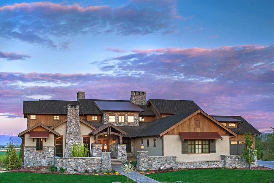 House plan exterior of a multi-story home with stone and wood facade, multiple gables, prominent stone chimney, and attached garage.
