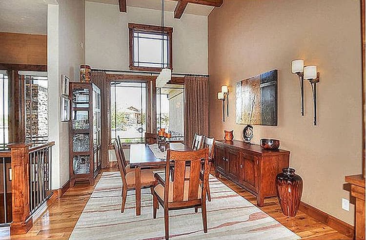 Dining room with vaulted ceiling, exposed beams, large windows, and wooden furniture.