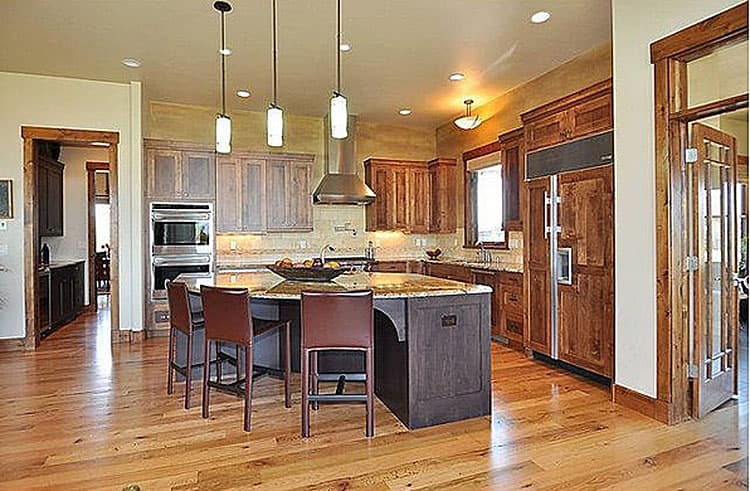 Kitchen with large island, custom wood cabinetry, stainless steel appliances, and pendant lighting.