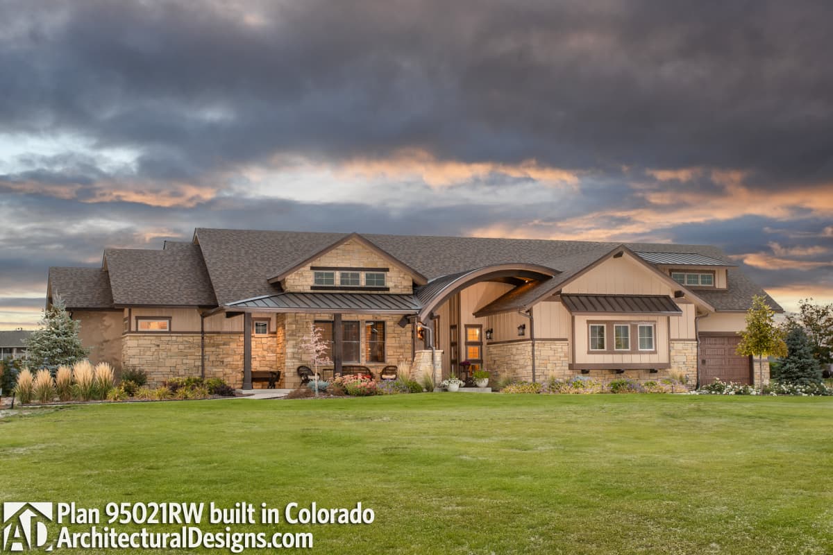House plan exterior: Ranch style with stone and stucco, covered porch, multiple gables, and a distinctive curved roof section.