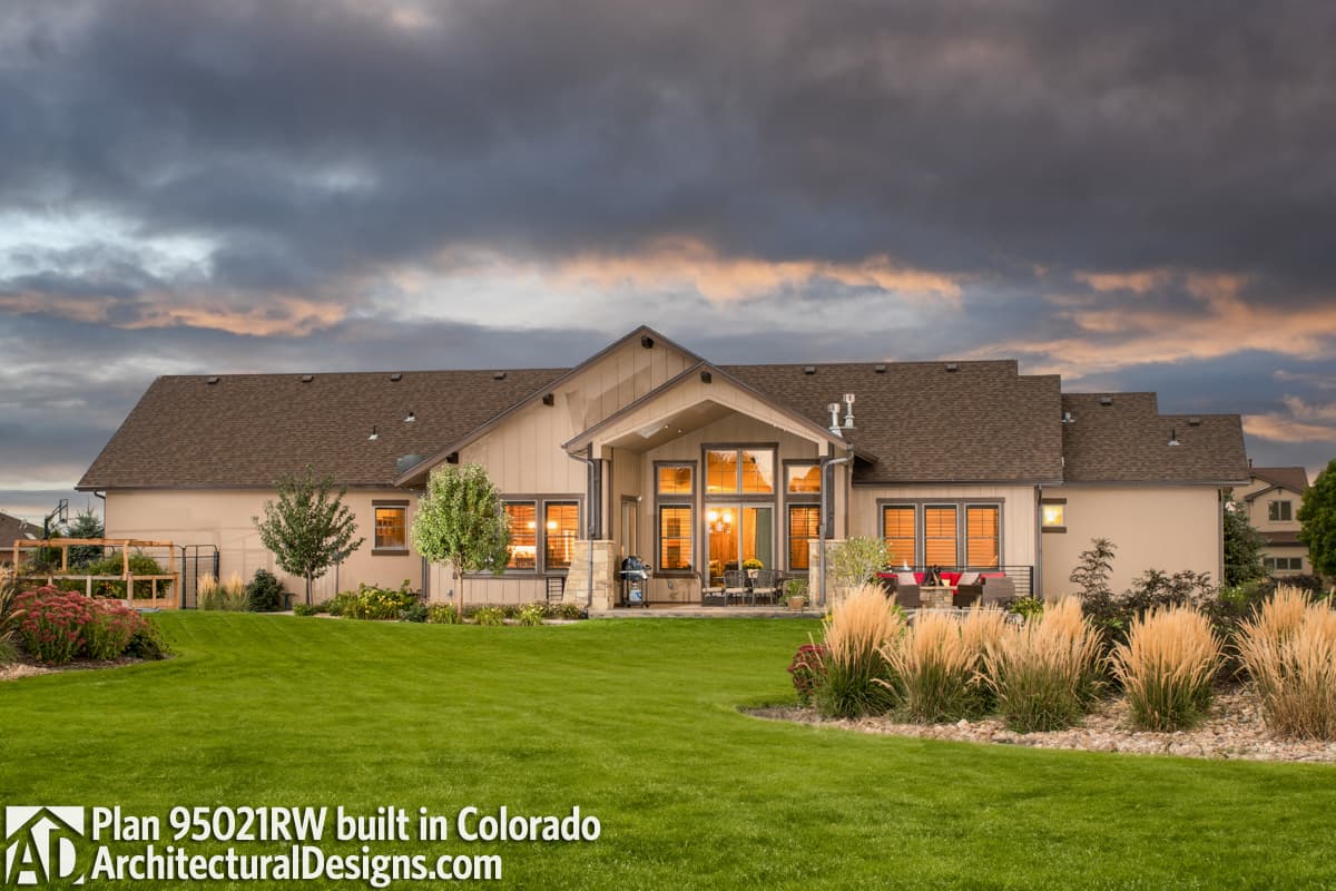 House plan exterior: Ranch style, one story, with prominent gabled central section, covered patio, and multiple large windows.