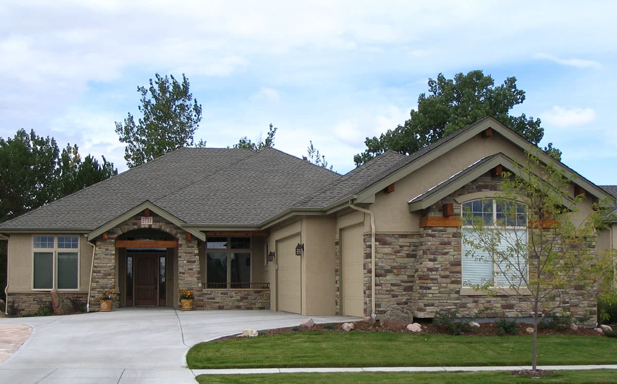 House plan exterior. Single-story with stone facade, arched entryway, gabled roof, and attached garage. Includes a concrete driveway.