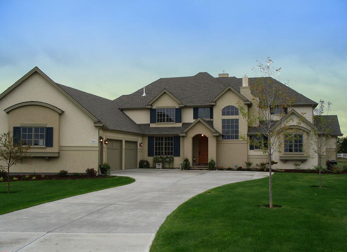 House plan exterior. Two-story stucco home with a curved driveway, arched window, and attached garage. Includes several gables and dormers.