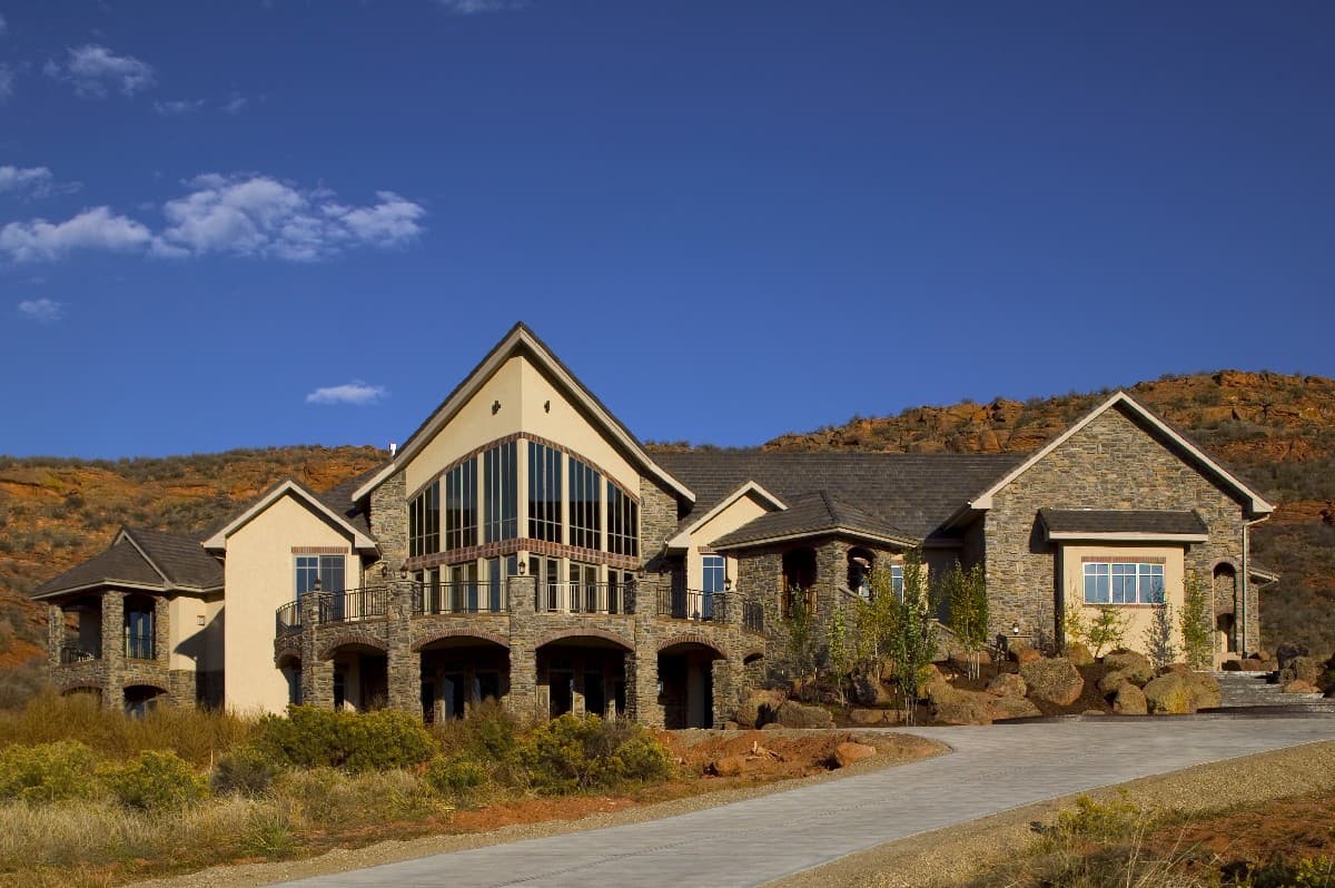 House plan exterior with stone facade, arched portico, and large multi-story window.