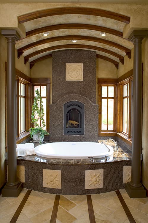 Bathroom with sunken tub, arched ceiling with wood beams, and fireplace.