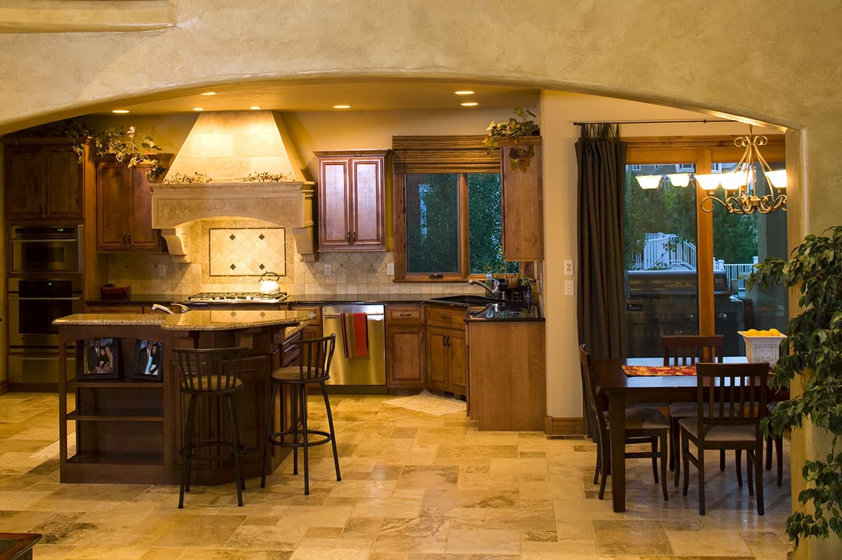 Kitchen with island, range hood, custom tile backsplash, and adjacent dining area with French doors to exterior.