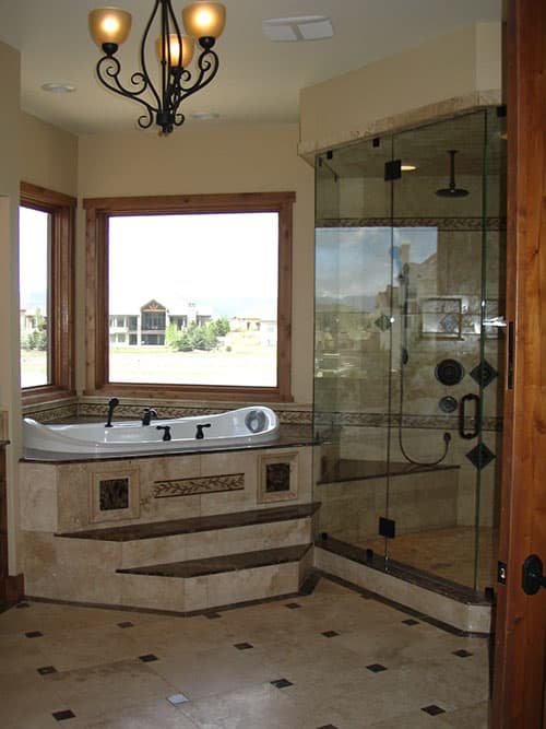 Bathroom with corner jacuzzi tub, glass-enclosed shower with multiple showerheads, and tiled floor.