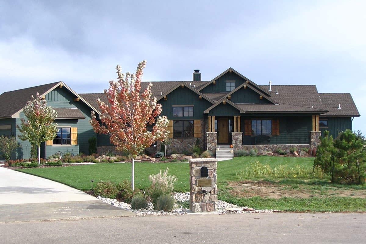 House plan exterior. Craftsman style, single story. Features include gables, covered porch with stone columns, and wood shutters.