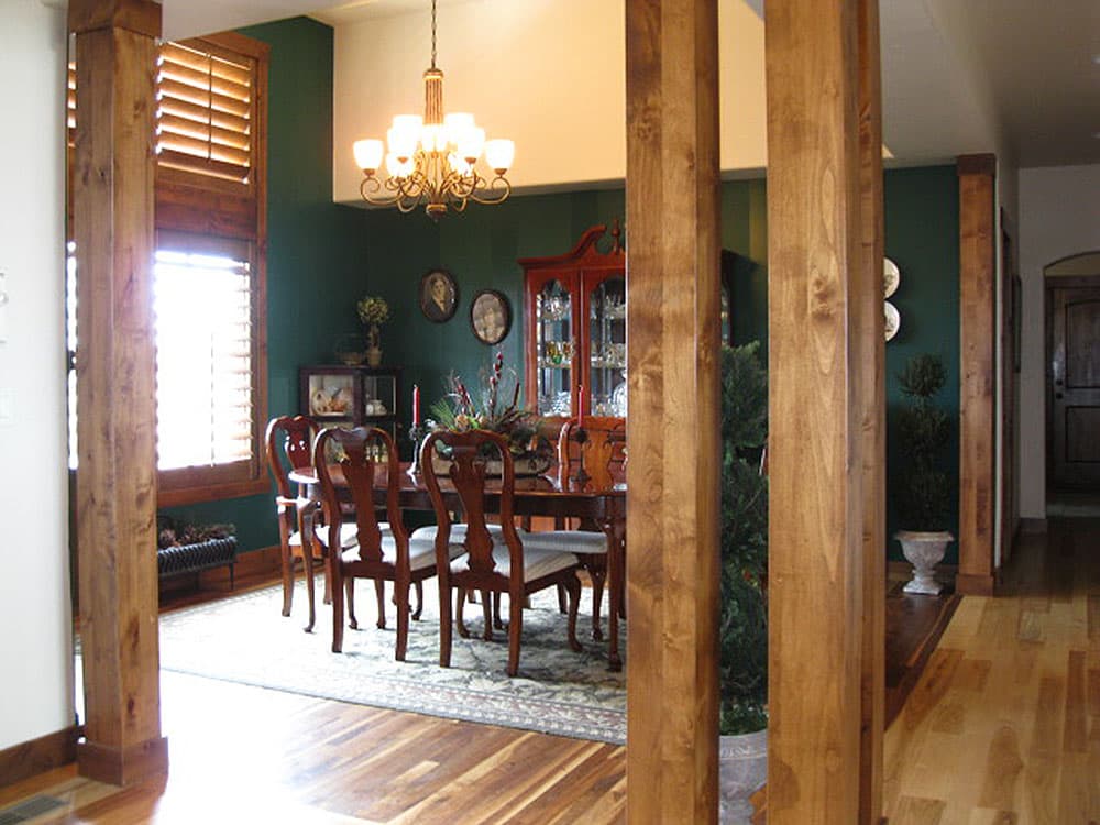 Interior view of dining room with wood pillars, chandelier, china cabinet, and dining set.