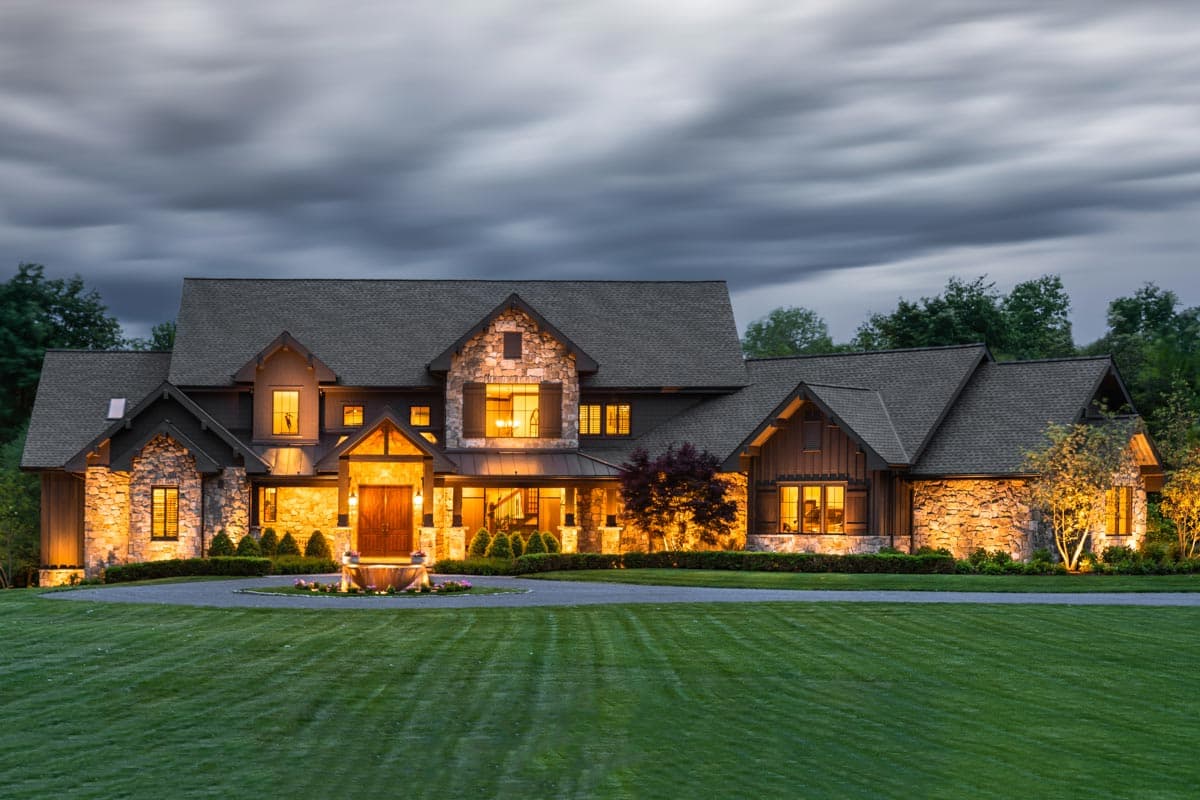 House plan exterior with stone and wood accents. Features include a covered porch, gabled rooflines, and multi-pane windows with shutters.