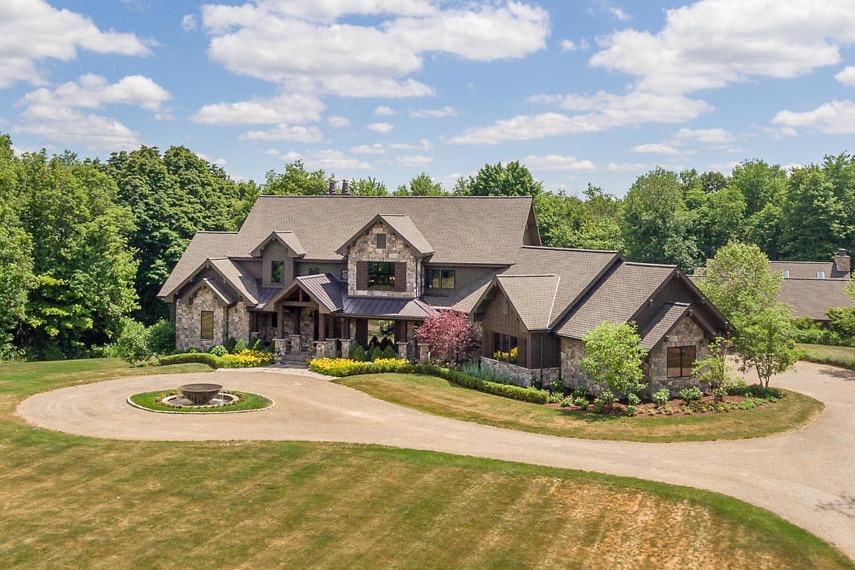 House plan exterior: Large lodge-style home with stone and wood siding, multiple gables, and a covered front entrance.