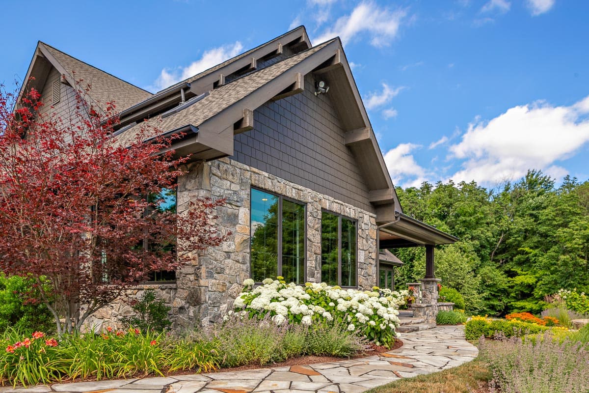 House plan exterior with stone base, gabled rooflines, large windows, and covered porch.