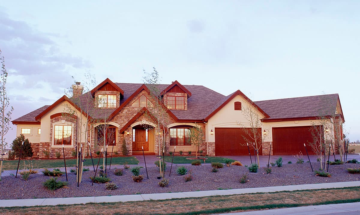 House plan exterior: Two-story home with stone accents, arched entryway, dormers, and a three-car garage.