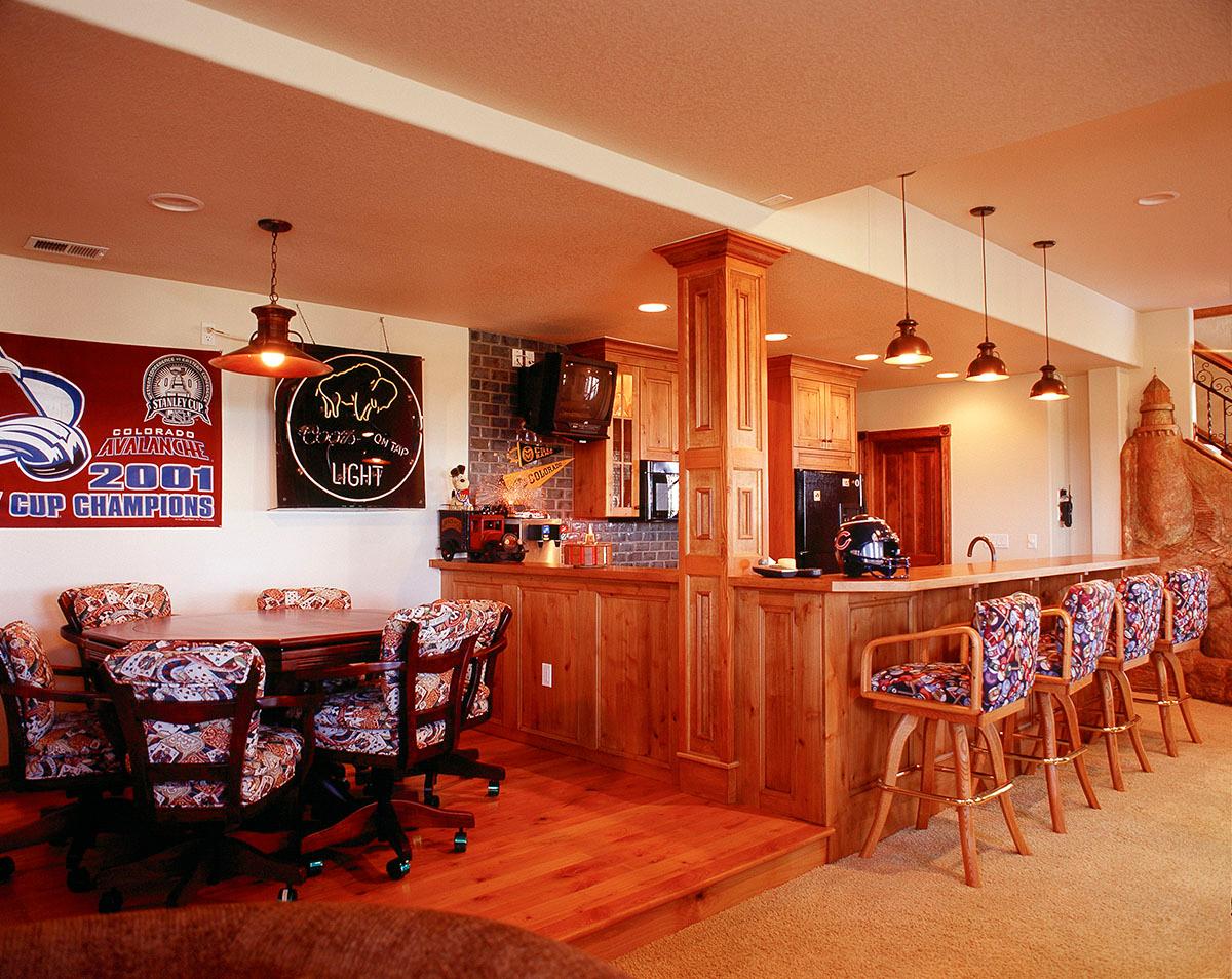 Entertainment area with a bar, stools, dining table, chairs, and cabinetry.