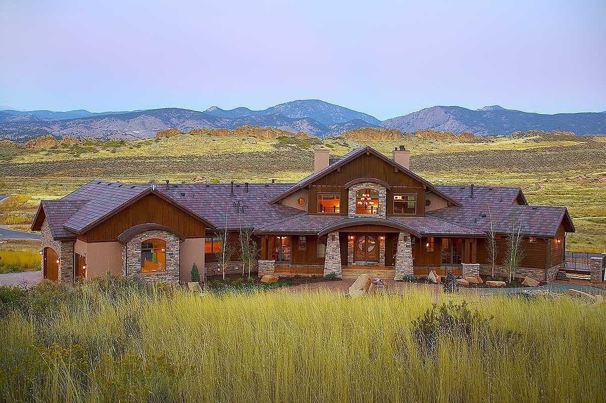 House plan exterior. Two-story home with Craftsman style elements: stone accents, arched entryway, gabled rooflines, and a covered porch.
