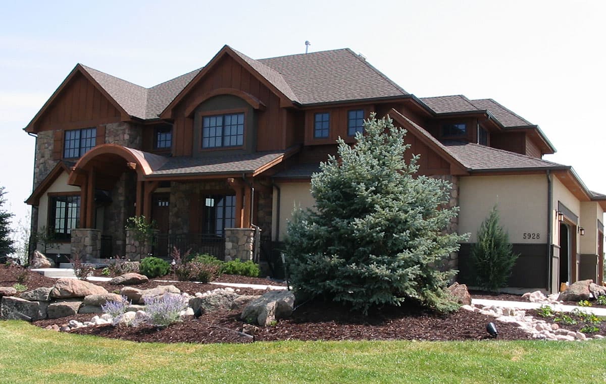 Craftsman style house plan exterior with stone accents, wood siding, multiple gables, and arched entryway.