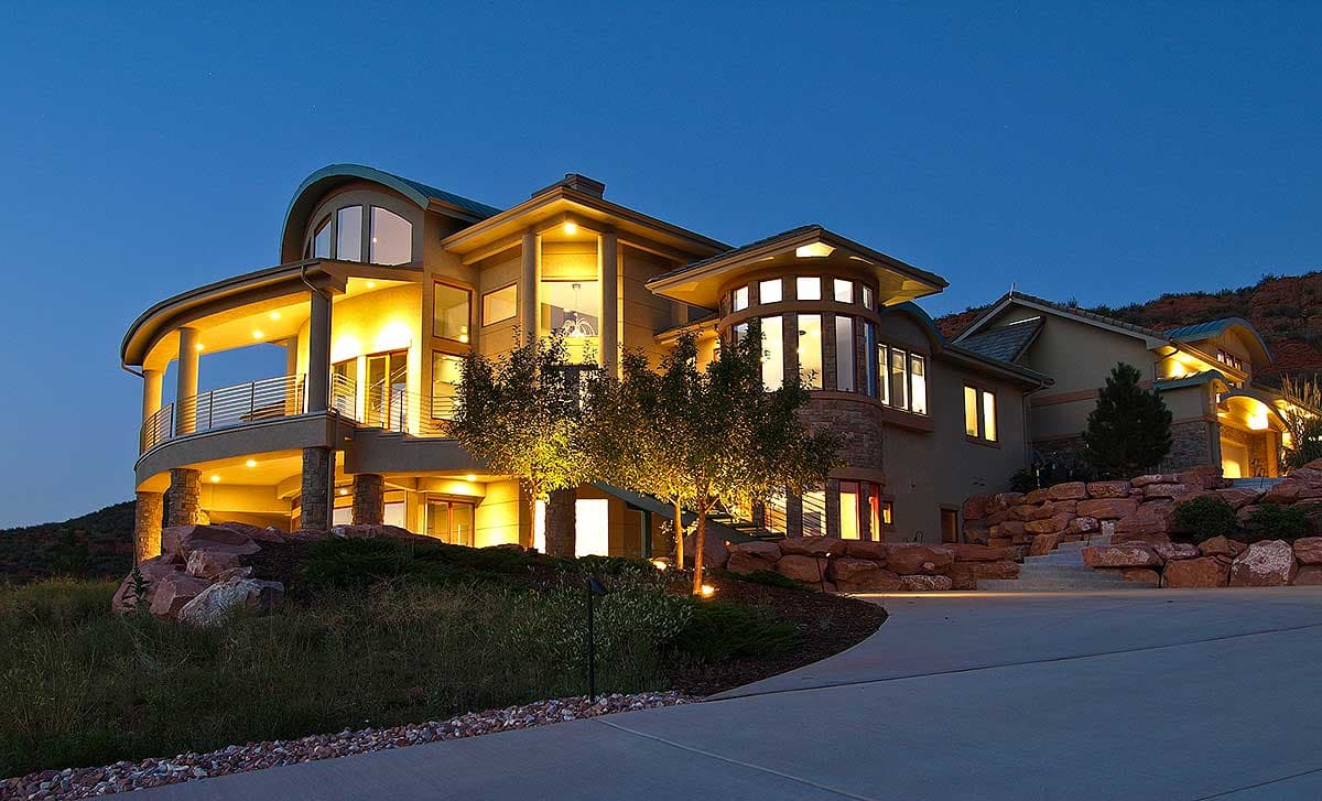 Exterior house plan with curved balcony, multi-story design, large windows, and prominent stone accents.