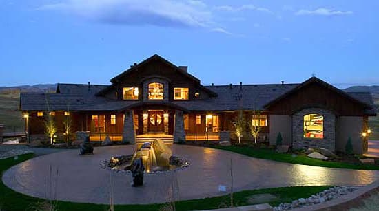 House plan exterior of a sprawling, single-story Modern Farmhouse with stone accents, a covered entry, and large arched windows.