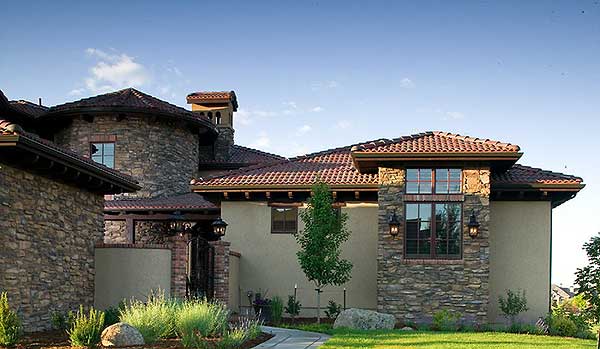 House plan exterior featuring stone and stucco, tile roof, multiple gables, and a round tower section.