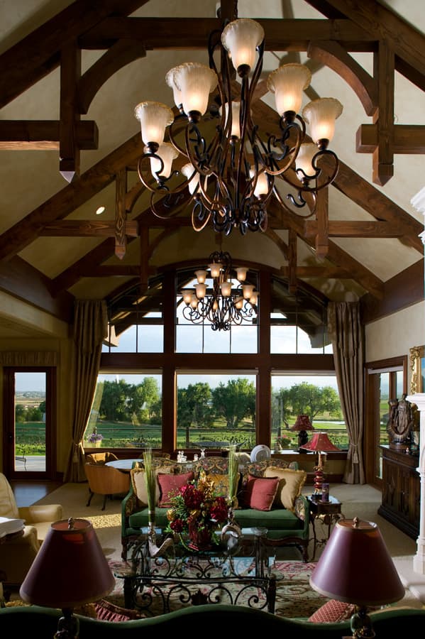 Interior rendering: Great room with vaulted beamed ceiling, large window wall, and ornate chandeliers.