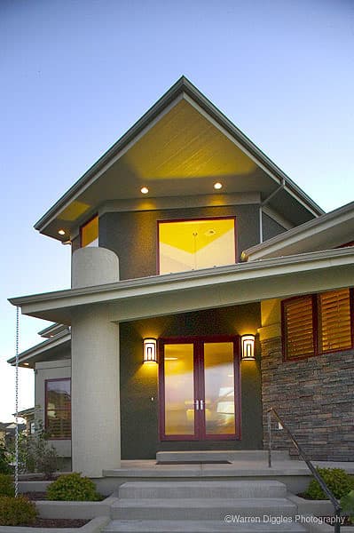 House plan exterior with large gabled roof, stone facade, double entry doors, and round corner accent.