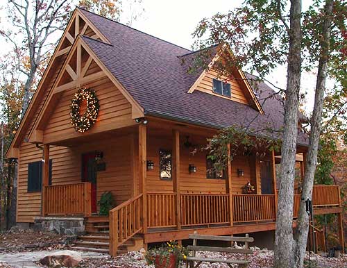 House plan exterior of a two-story wooden cabin with a prominent gable, exposed rafter tails, and a wrap-around porch.