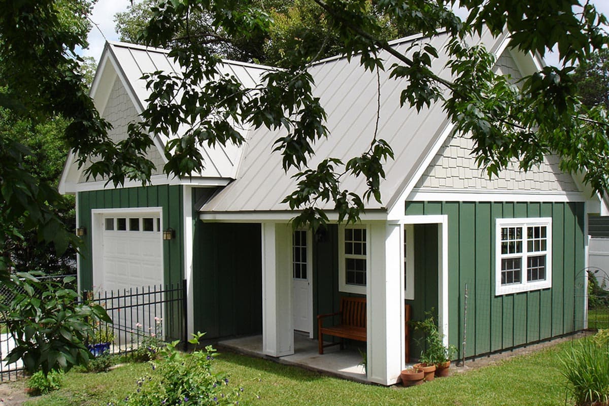 House plan exterior featuring a detached garage, covered porch with columns, gable ends with scallops, and vertical siding.